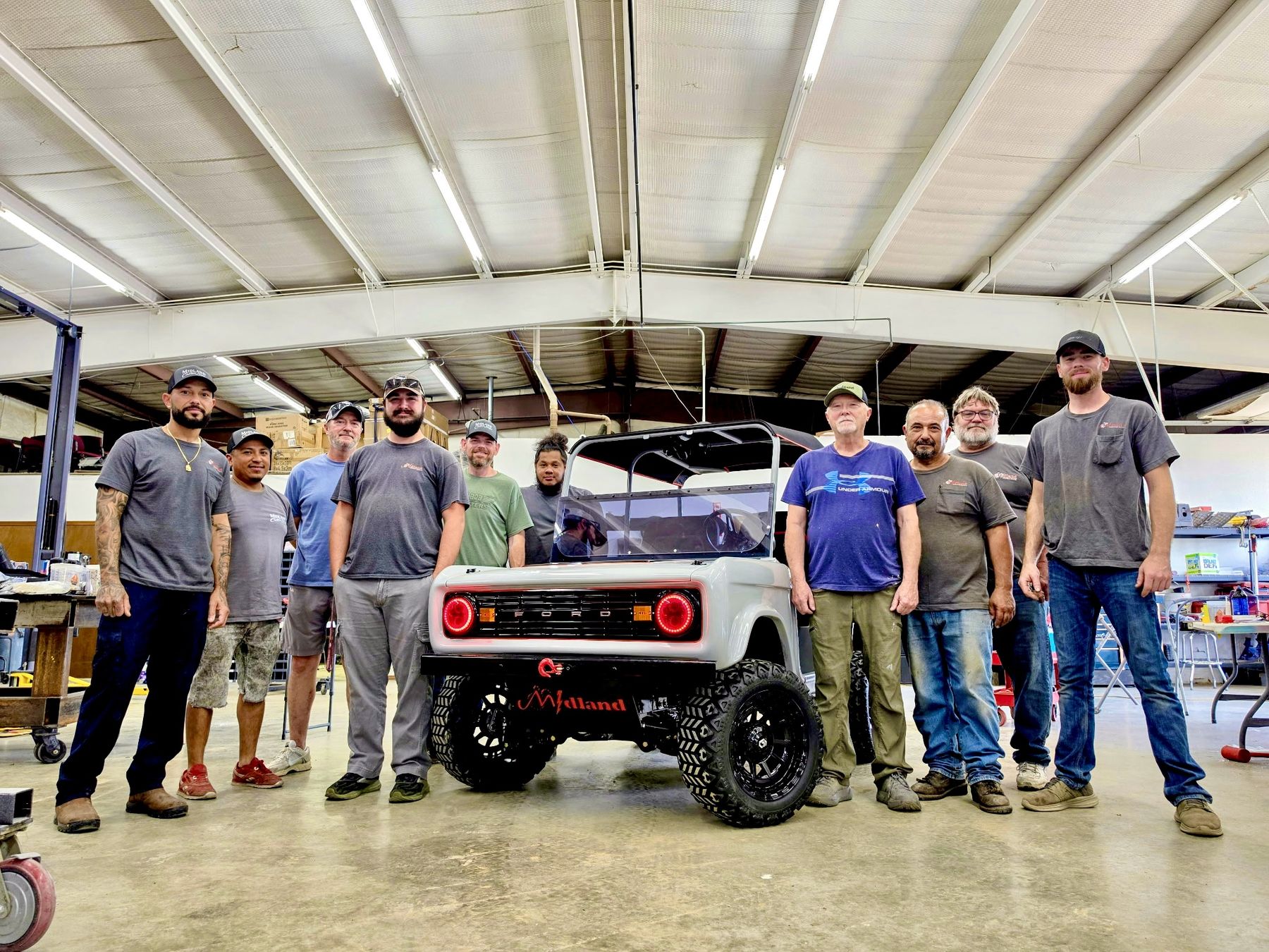 The Midland Custom Shop crew standing with a custom Bronco style golf cart build inside the fabrication shop