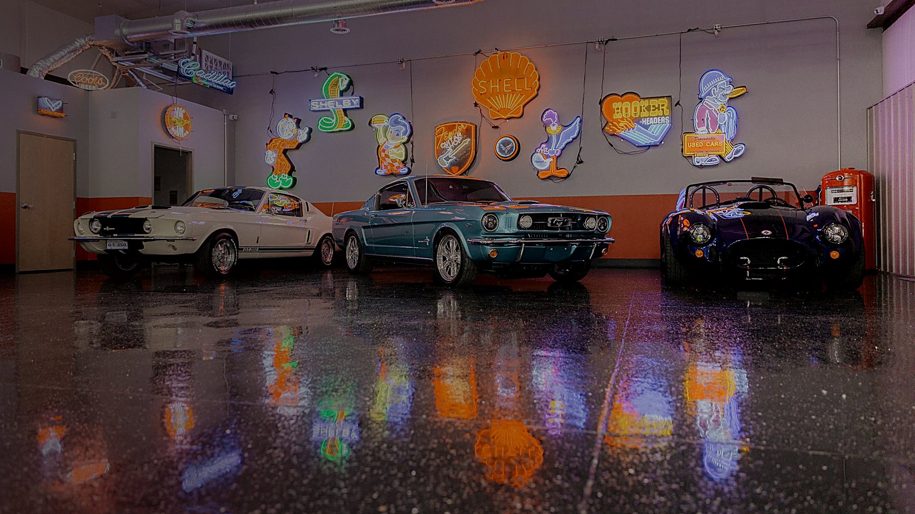 A 1965 Mustang fastback between a Shelby GT350 and a Cobra roadster in the Midland Custom Shop showroom